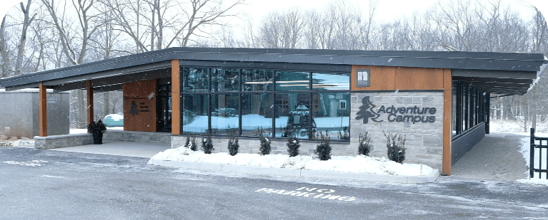 Exterior view of the Adventure Campus building in winter, with snow on the ground and the Adventure Campus sign visible on the front entrance.