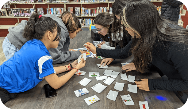 Students working together on a card-matching activity at a table in a school library.
