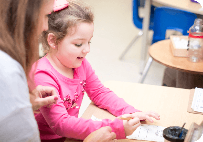 Young student completing a classroom activity with support from an educator.