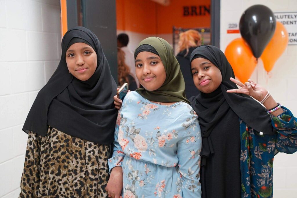 Three students posing together in a school hallway during a school event.