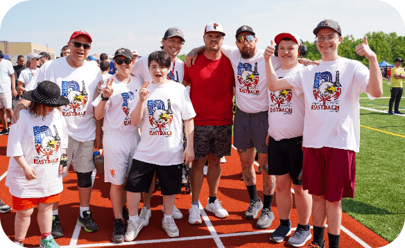 Group of students and adults standing together on a running track during a Special Olympics event.