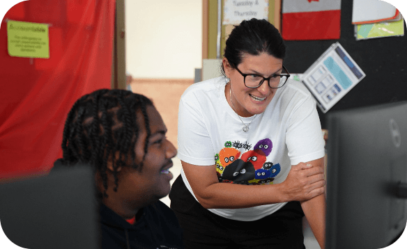 Educator supporting a student during a computer-based learning activity.